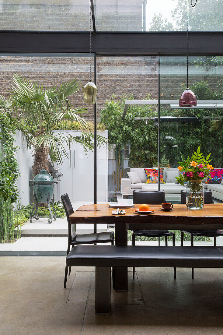 Black bench at wooden table with view through windows of conservatory extension in Victorian townhouse London UK