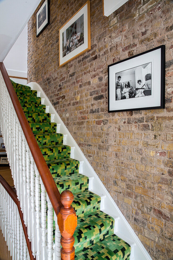Framed prints above black and green geometric carpeting on staircase in Victorian London townhouse UK