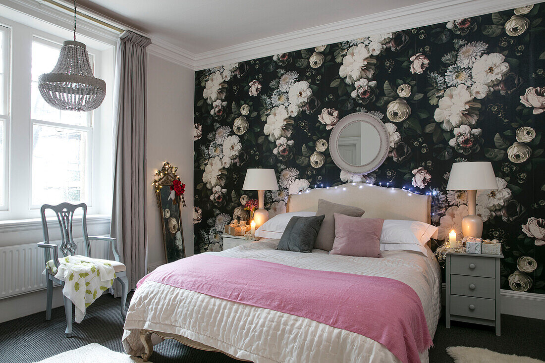 Geblümte Wand mit Doppelbett und rosa Decke in einer Wohnung in Hove, East Sussex, UK