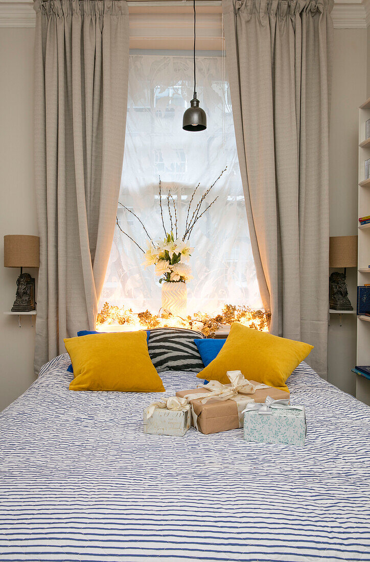Gelbe Kissen auf Bett mit Geschenken in Hove Wohnung East Sussex UK