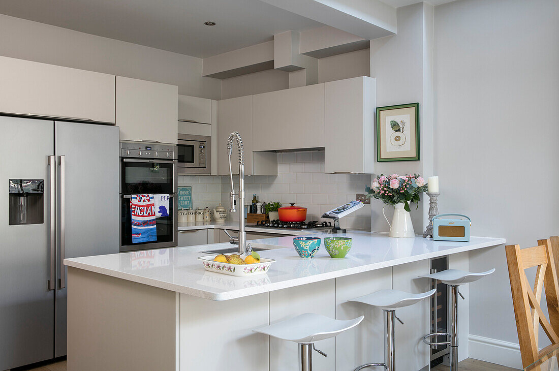 Kühlschrank und Wasserhahn mit Hockern an der Frühstücksbar in der Küche eines Londoner Hauses UK