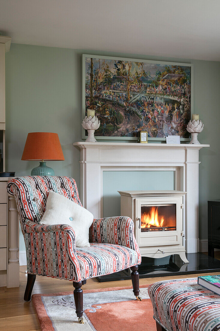 Upholstered armchair and lit woodburning stove in Wiltshire living room