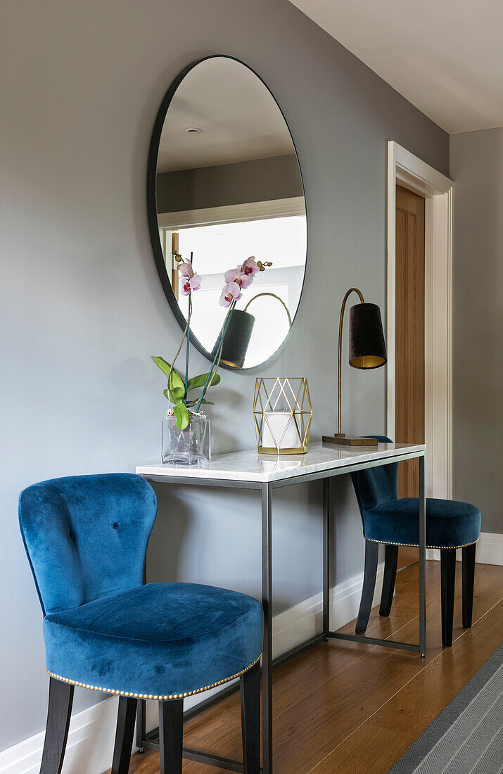 Blaue Samtstühle und großer Spiegel mit Konsole im Flur eines Hauses in Surrey UK