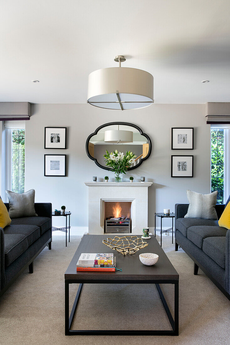 Zwei graue Sofas mit Couchtisch und Kamin im Wohnzimmer eines Hauses in Surrey, Großbritannien