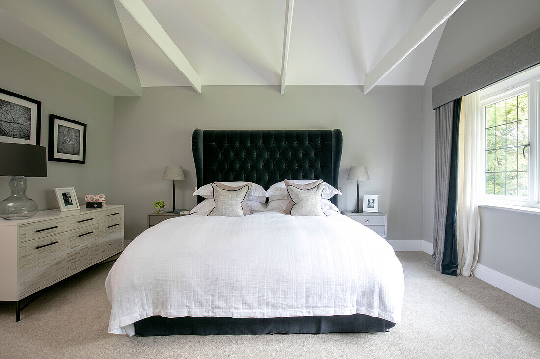 Dunkelgrünes geknöpftes Kopfteil mit weißen Bezügen auf dem Bett in einem Haus in Surrey UK