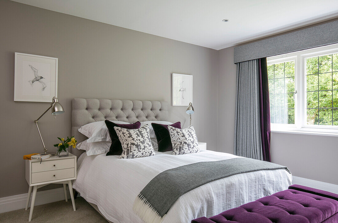 Doppelbett mit grauer Decke und Kunstwerk mit Vögeln am Fenster in einem Haus in Surrey UK