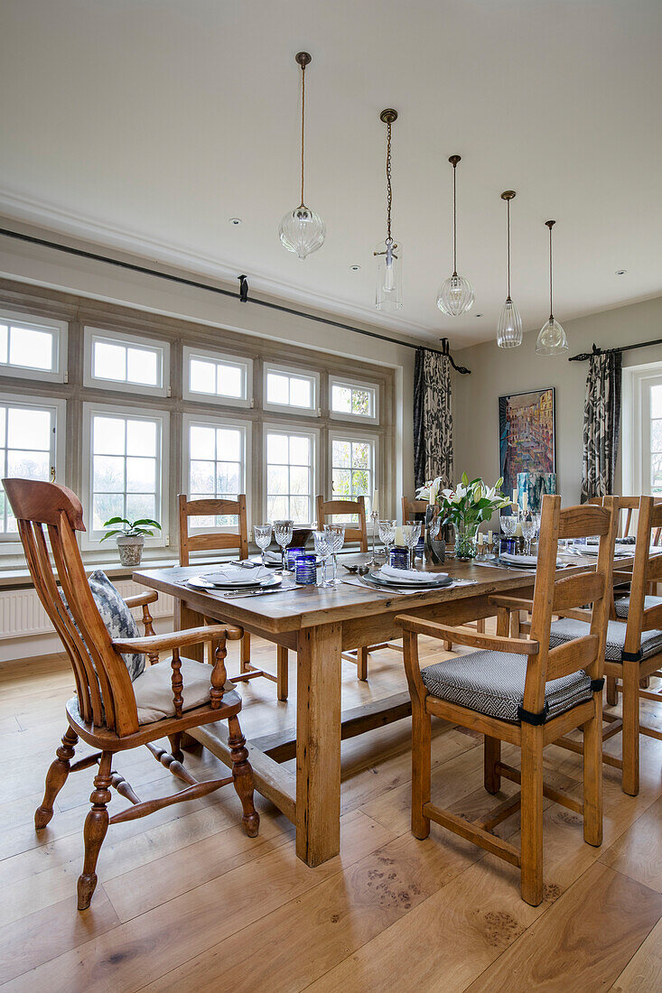 Esstisch und Stühle aus Holz mit Glaspendelleuchten in einem Haus in West Sussex, Großbritannien