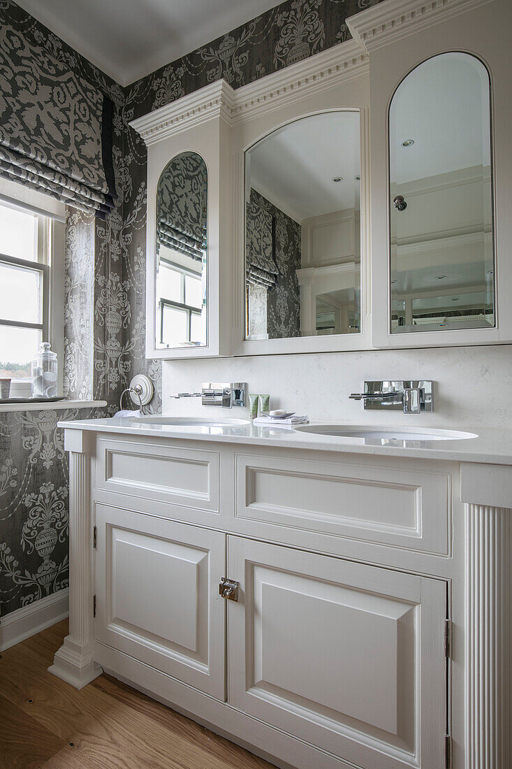 Doppelwaschbecken mit Spiegelschränken und grauer Tapete und Jalousien in einem Haus in West Sussex UK