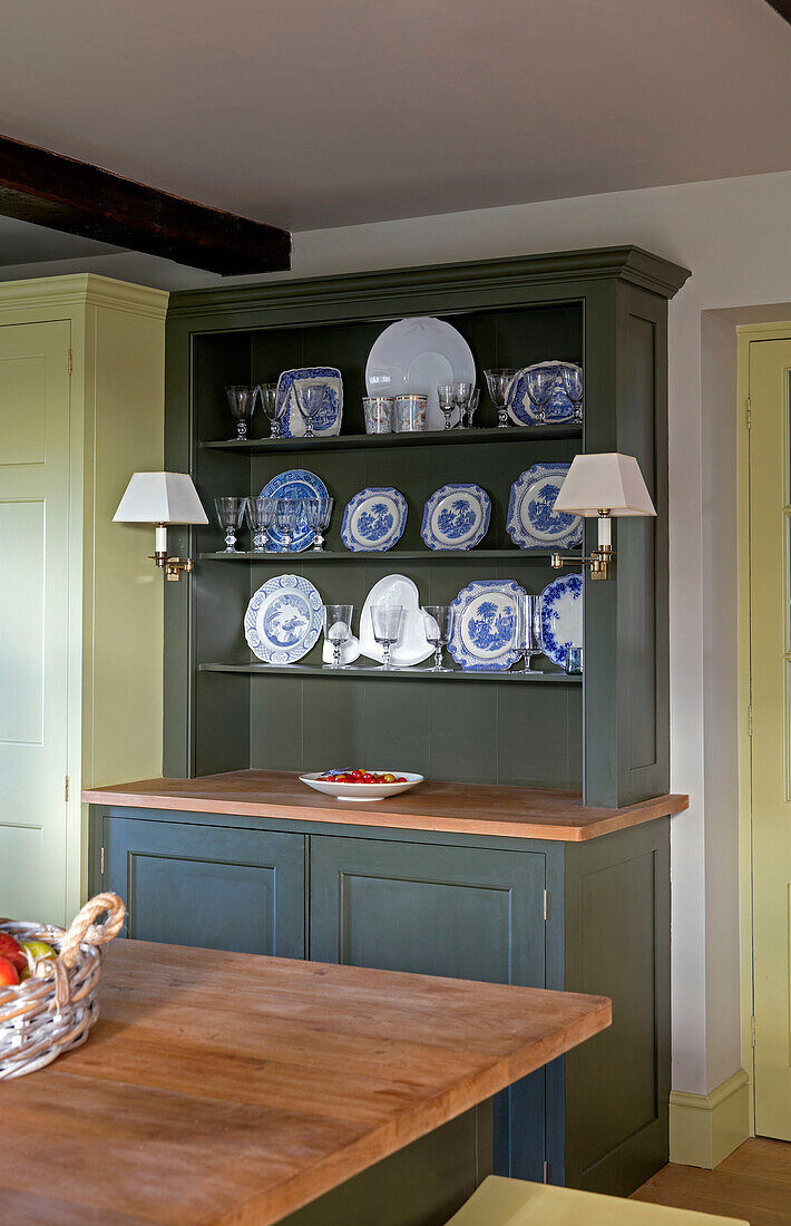Teller und Gläser auf dunkelgrüner Küchenkommode in einem Haus in Somerset, England
