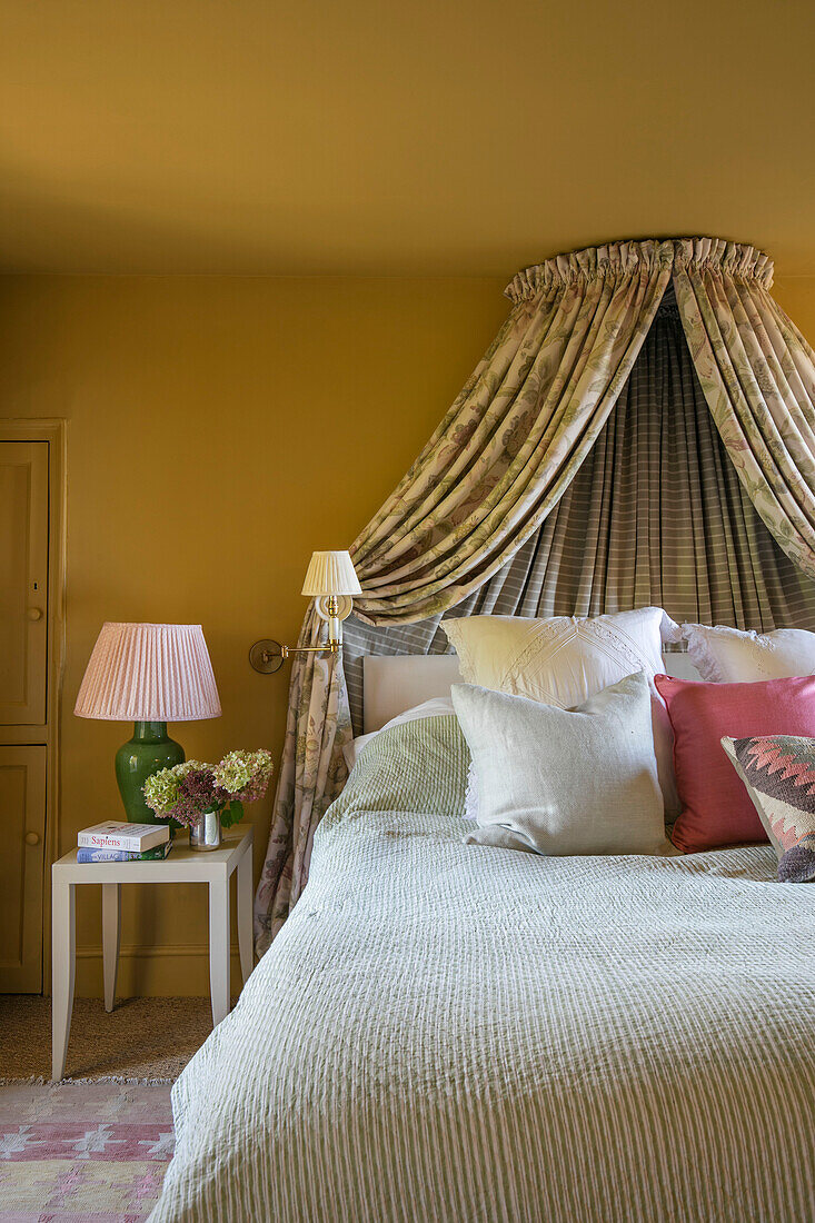 Doppelbett mit Baldachin im gelben Zimmer eines Hauses in Somerset, UK