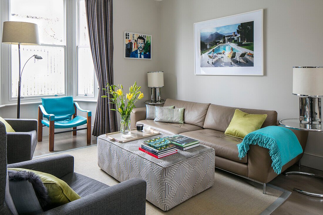 Gerahmtes Kunstwerk über dem Sofa mit türkisfarbener Decke und Stuhl im Erkerfenster eines Hauses in London UK