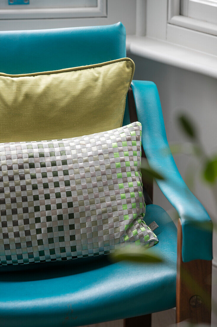 Cushions on turquoise leather chair in window of London home UK