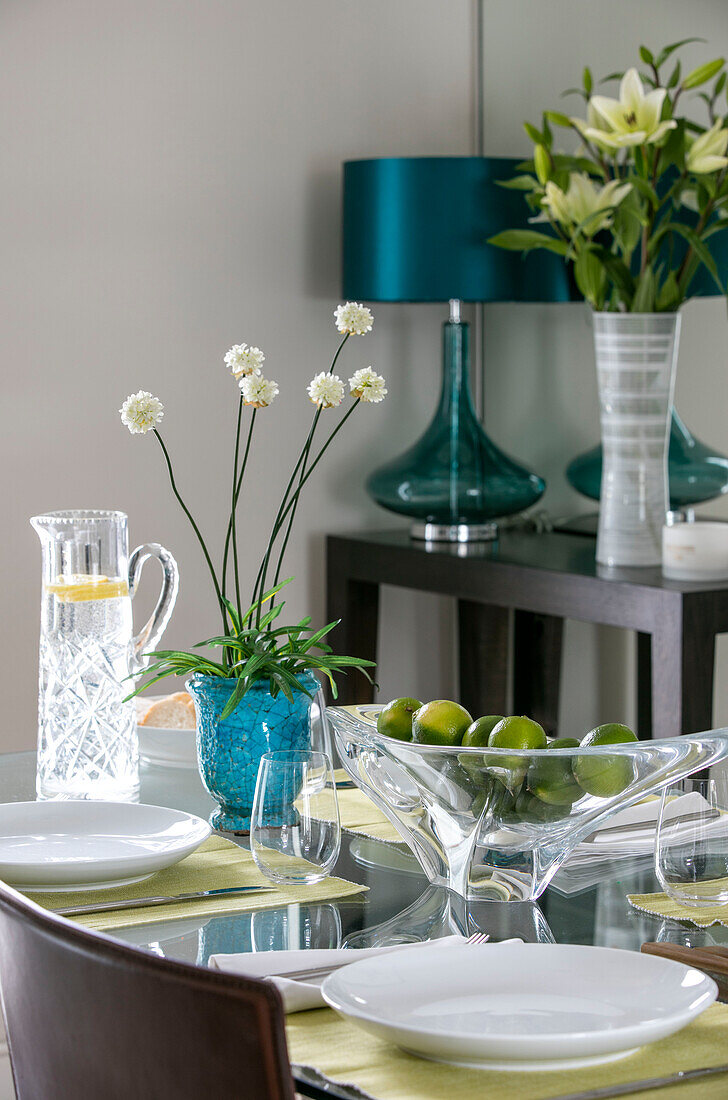 Tealfarbene Lampe und Pflanzentopf mit Limetten auf dem Esstisch in einem Londoner Haus UK