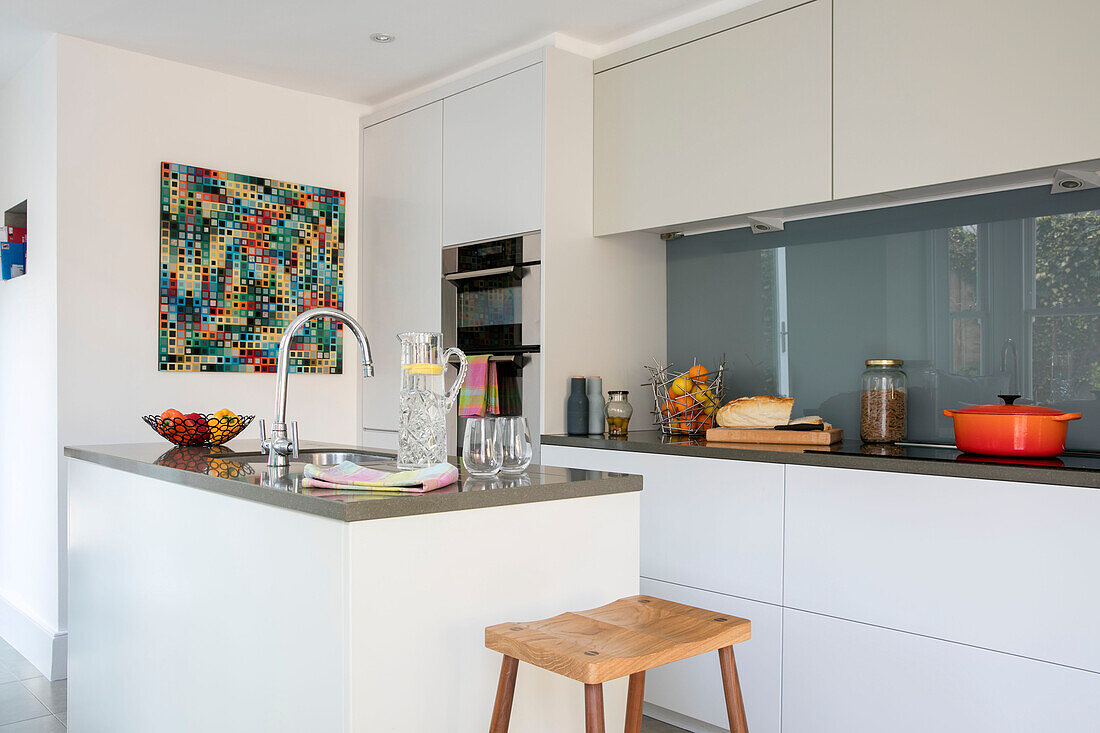 Holzhocker an der Kücheninsel mit moderner Kunst in einem Haus in London UK