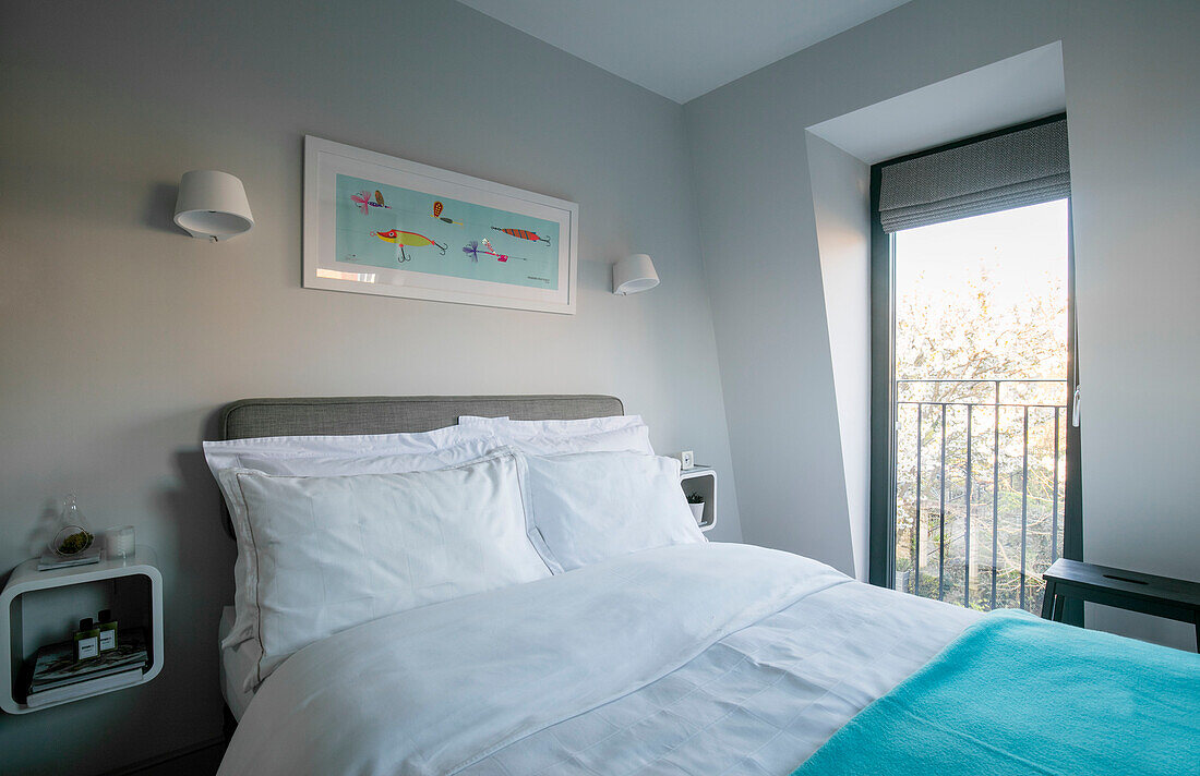 Kunstwerk über dem Doppelbett mit türkisfarbener Decke am Fenster in einem Londoner Haus UK