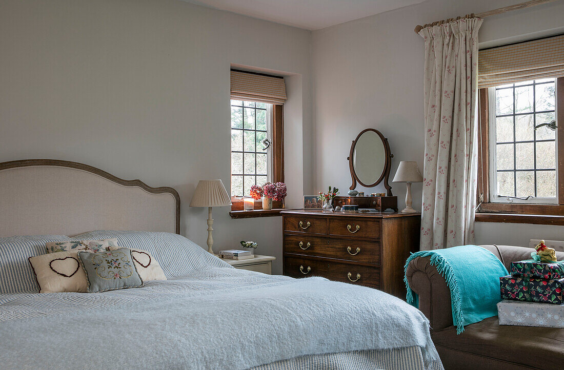 Doppelbett mit hellblauer Decke und Holzkommode in einem Haus im Arts-and-Crafts-Stil in West Sussex, England