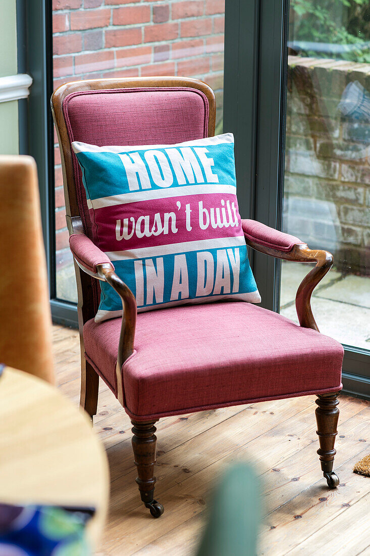 "Home wasn't built in a day (Das Haus wurde nicht an einem Tag erbaut) Kissen auf rosa Sessel in einem Haus im Arts-and-Crafts-Stil Sevenoaks Kent UK"""