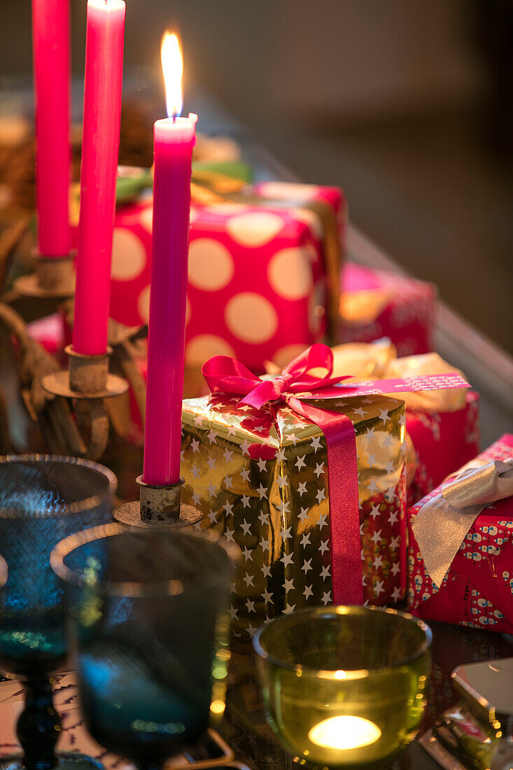 Hellrosa Kerzen und eingepackte Weihnachtsgeschenke in einem Haus in East Dulwich, London UK