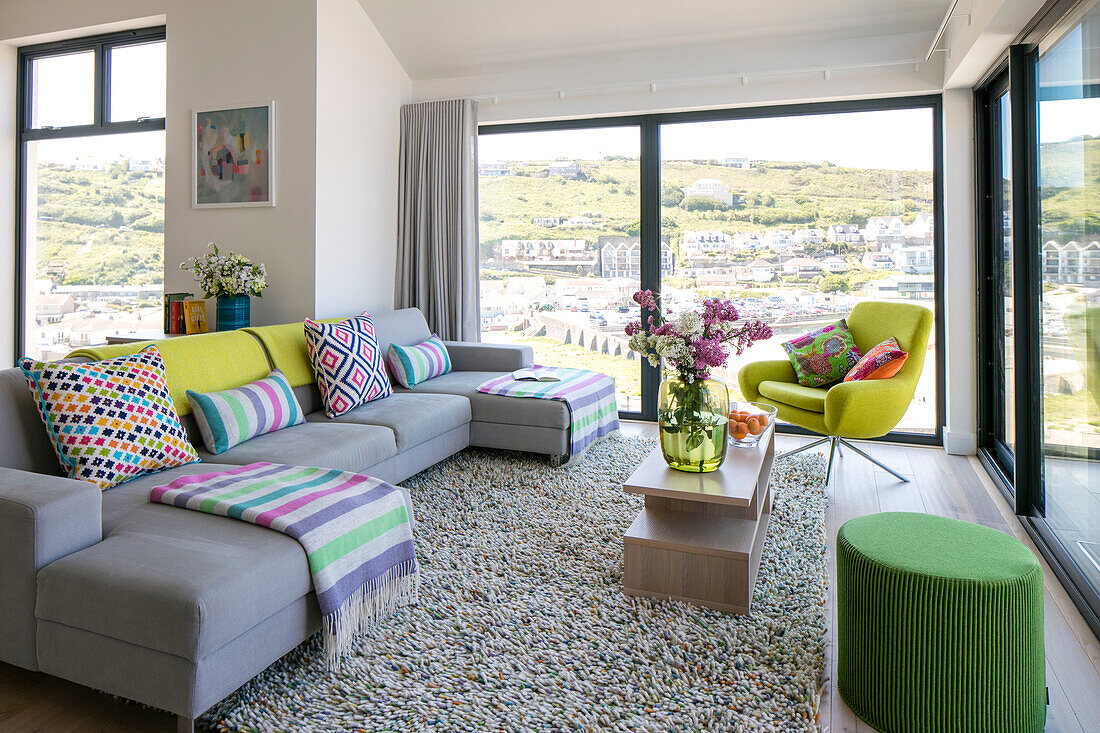 Light grey sofa in living room with view of coastal hillside Cornwall UK