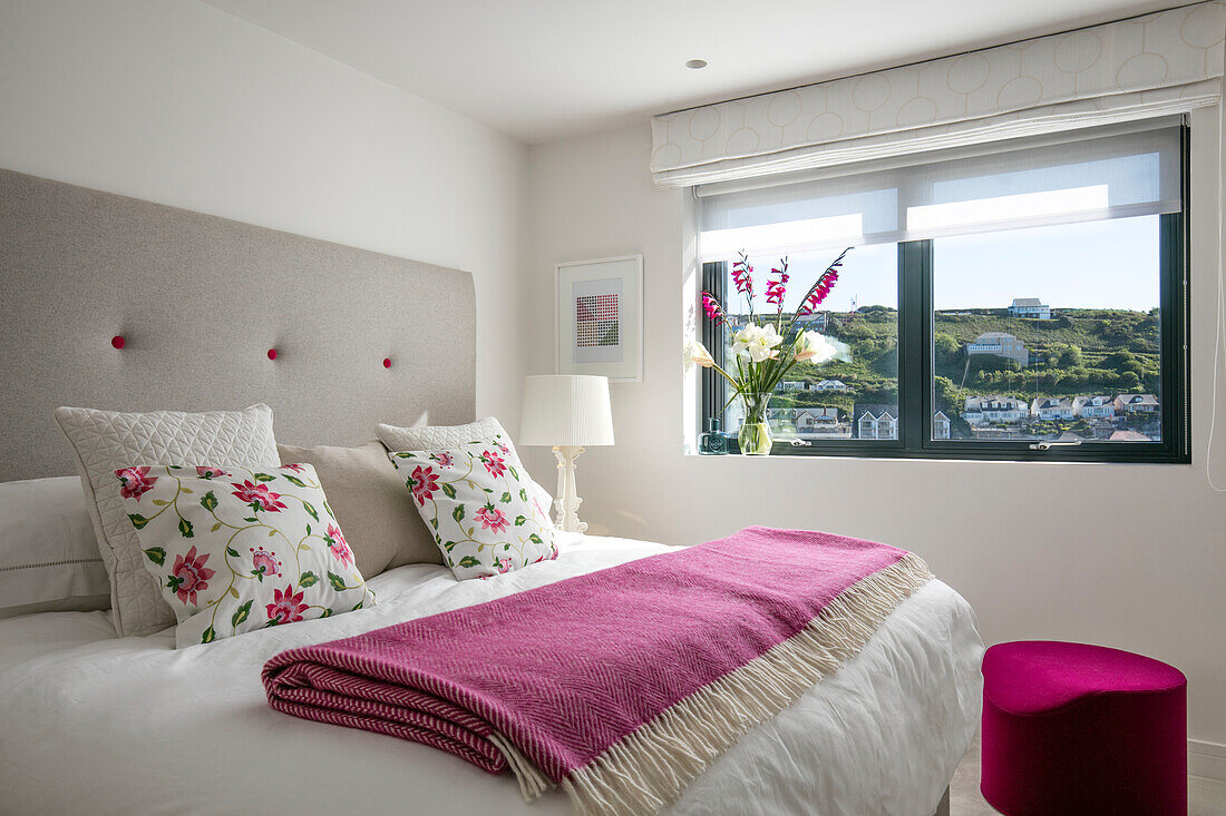 Rosa Decke gefaltet auf Doppelbett mit Blumenkissen und Blick auf Cornwall UK