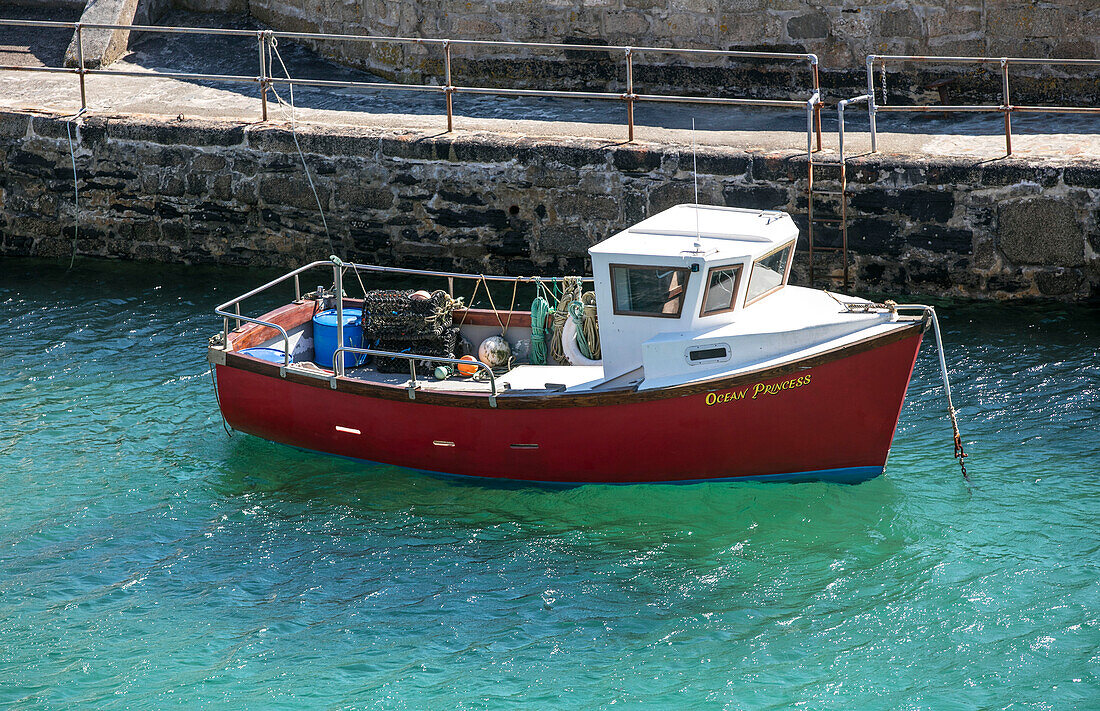 Rotes Fischerboot an der Hafenmauer Cornwall UK