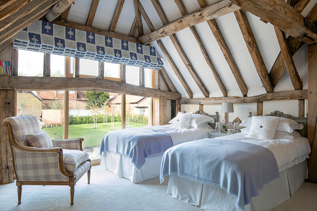 Zweibettzimmer mit gepolstertem Sessel in einer umgebauten Scheune in Hampshire UK