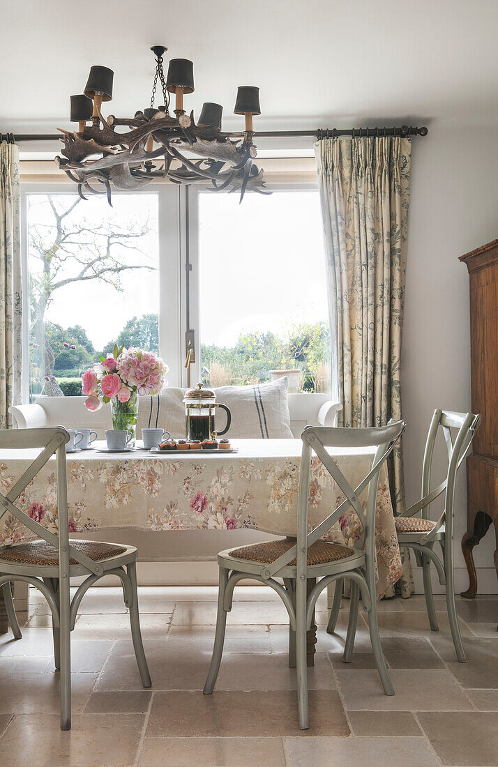 Bemalte Stühle am Tisch mit Blumentuch in einem Haus in Oxfordshire, England