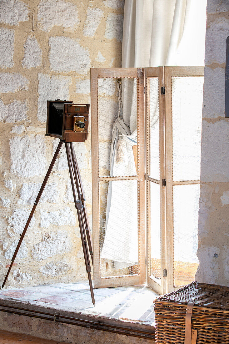 Vintage camera on tripod and folding screen on window seat in 13th century medieval house Dordogne France