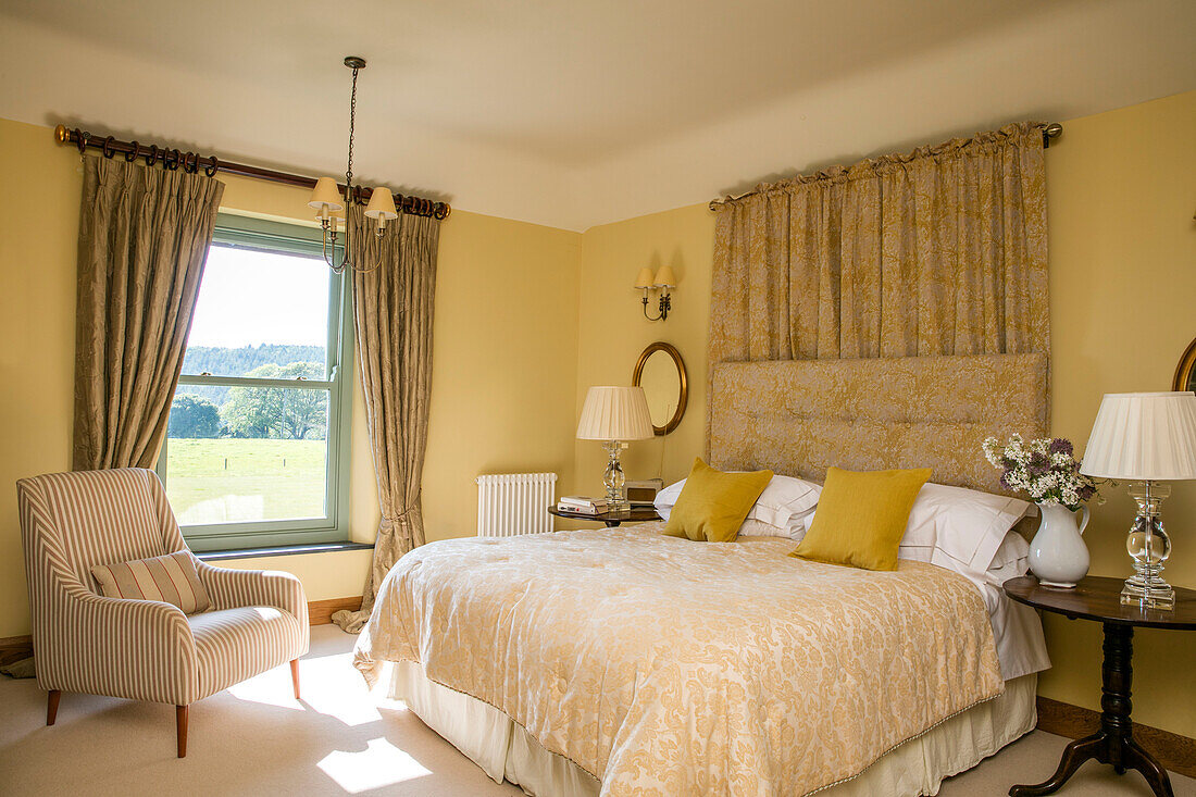 Striped armchair at window in yellow Devon bedroom UK