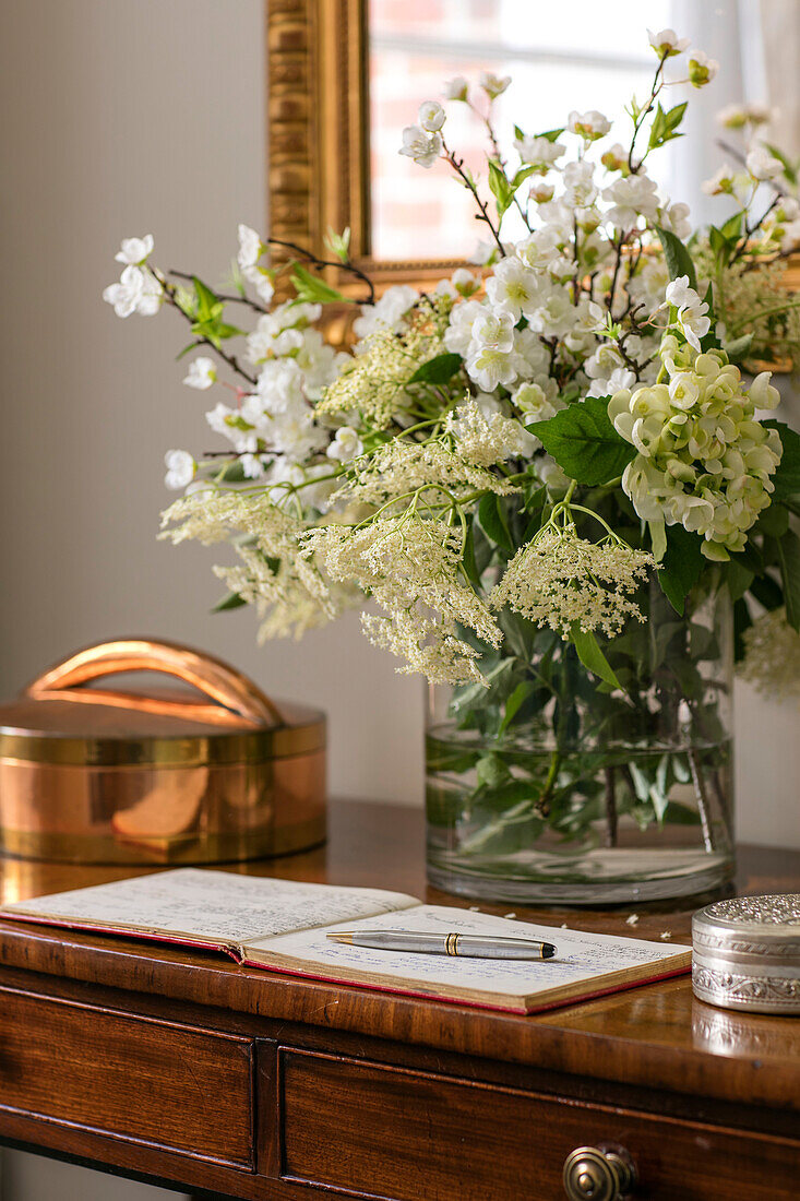 White flowers and address book on wooden hallway table in Hampshire home UK