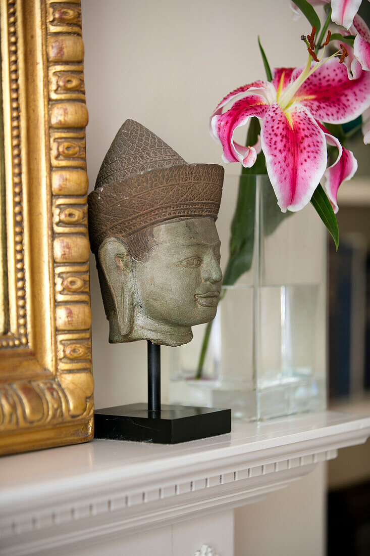 Geschnitzter asiatischer Kopf und geschnittene Orchidee mit Spiegelrahmen in einem Haus in Hampshire, UK