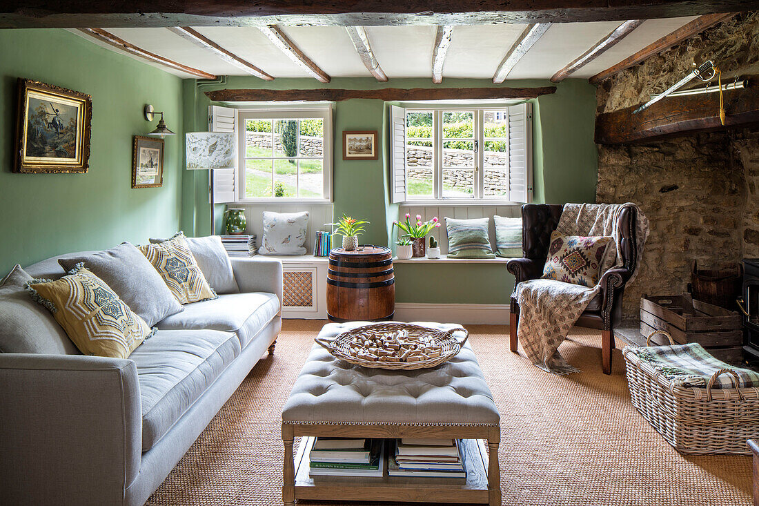 Light grey sofa and ottoman in beamed living room of 17th century Northamptonshire cottage UK