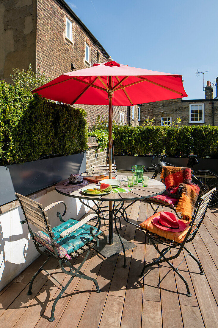 Gartenmöbel auf einer viktorianischen Terrasse im Norden Londons mit rotem Sonnenschirm UK