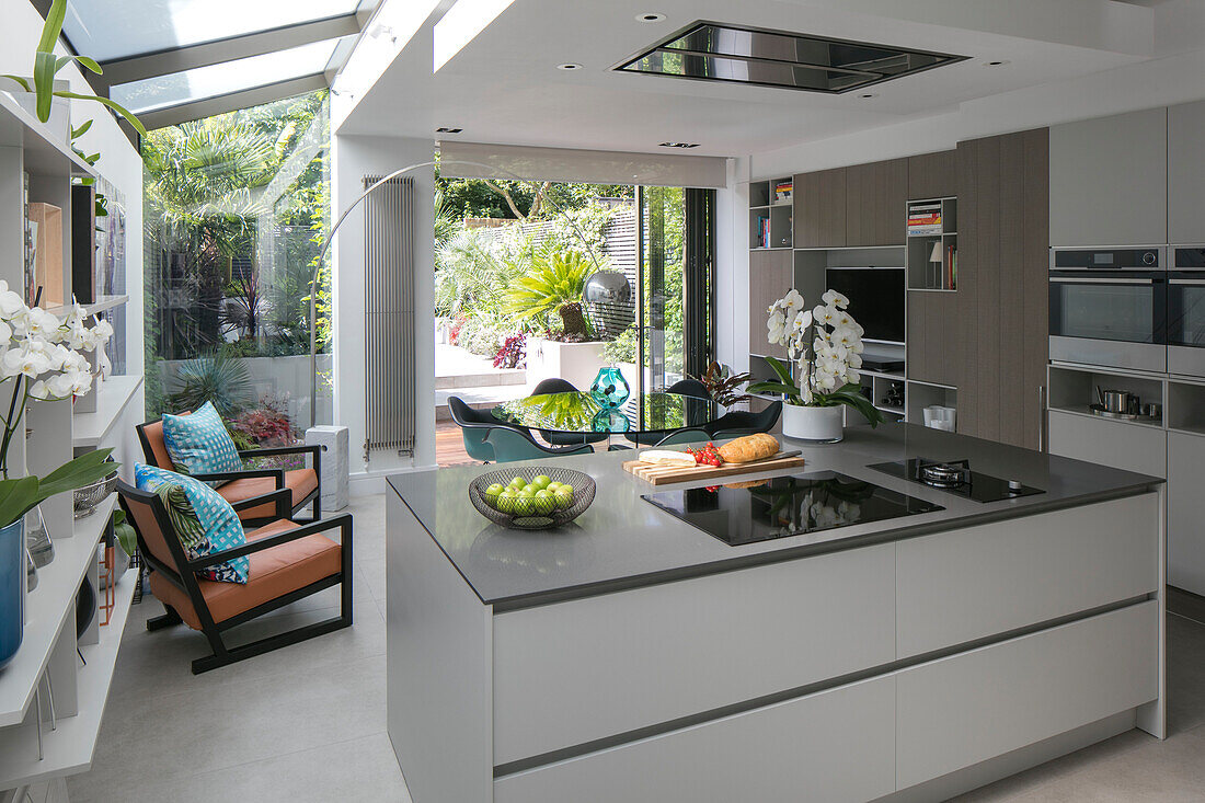 Open plan kitchen extension with retro style chairs and garden view in London home UK