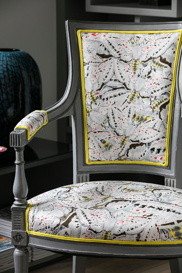 Grauer Stuhl mit geblümtem Stoffbezug und gelber Zierleiste in einem Haus in London, UK