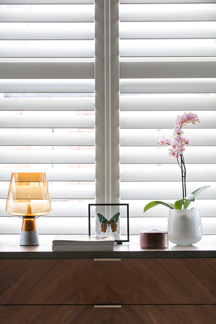 Retro-Lampe und Orchidee auf hölzerner Anrichte in einem Haus in London UK