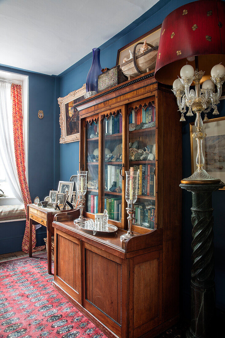 Antike Laternen und Bücherregal mit Glasfront in einem Haus in Sussex, UK