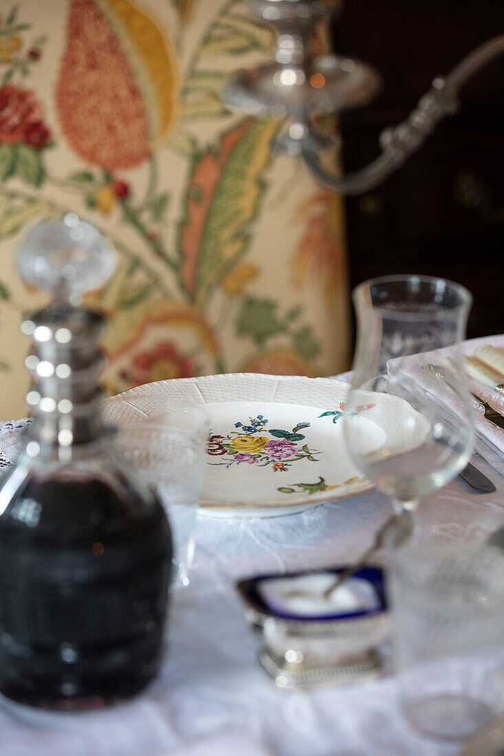 Decanter of red wine with china plate on dining table in Sussex home