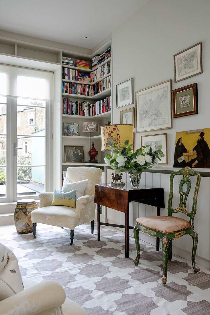 Vintage-Stühle und Klapptisch mit Bücherregalen im Eingangsbereich eines Londoner Hauses UK