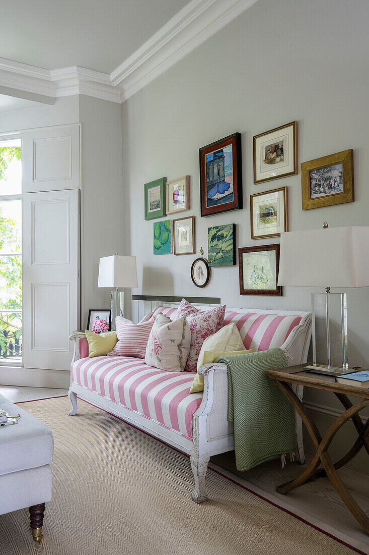 Picture wall and pink and white striped sofa in London living room UK