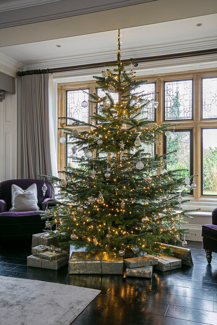 In Geschenkpapier verpackte Geschenke unter einem großen Weihnachtsbaum in einem Haus in Hampshire, UK