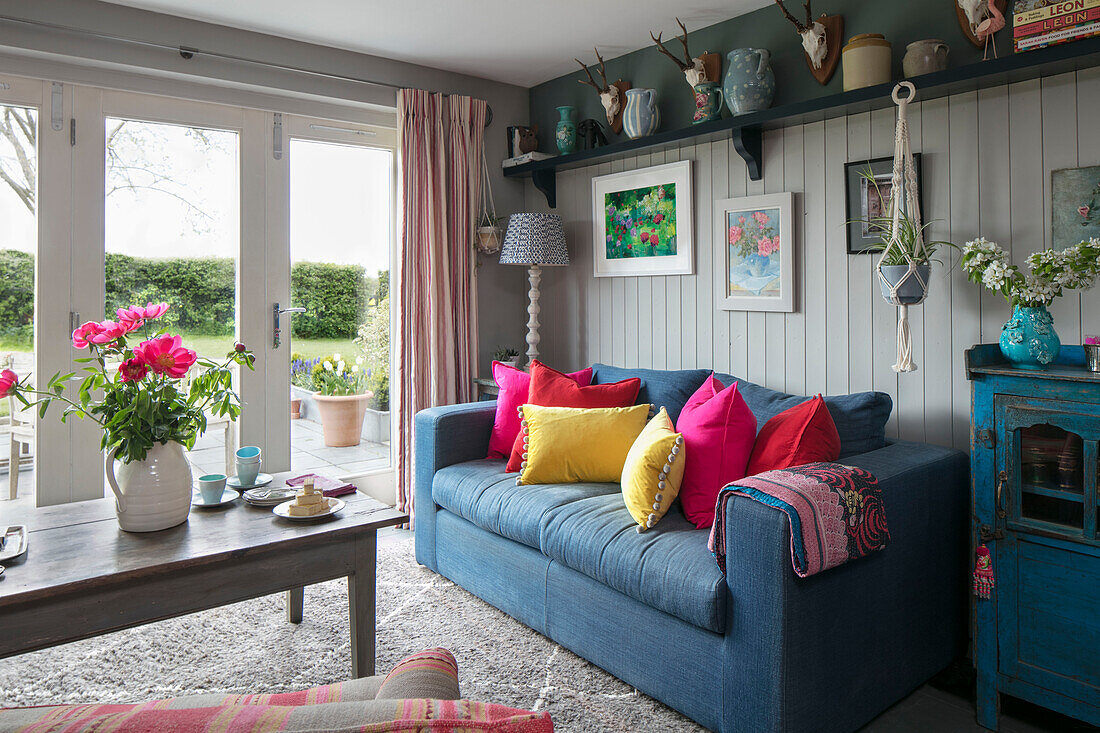 Grey sofa with bright cushions and coffee table at patio doors in Hampshire home England UK