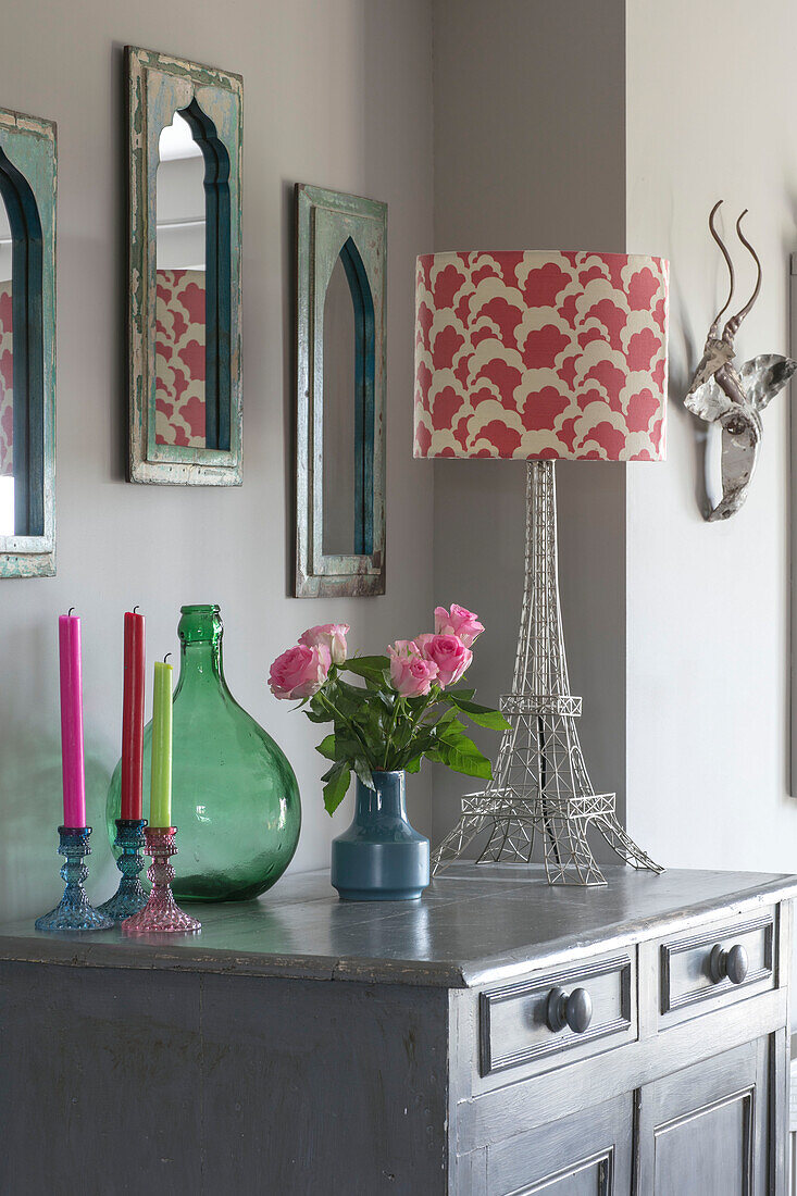 Candles and lamp on grey sideboard with Moroccan style mirrors in Hampshire home England UK