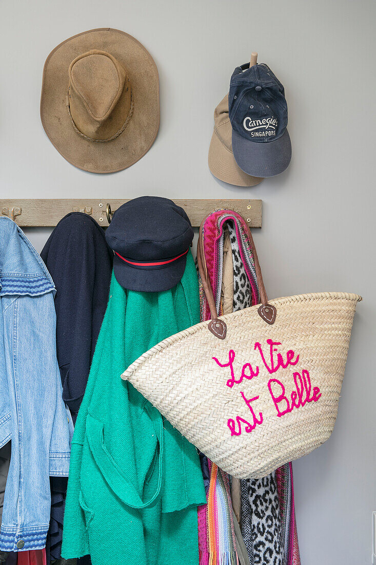 Jackets and hats hang with shopping bag in hallway of Hampshire home England UK