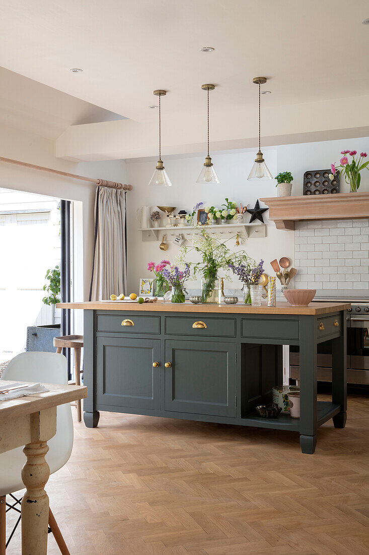 Kücheninsel und Parkettboden mit Schnittblumen in der Küche eines unter Denkmalschutz stehenden Landhauses in Hertfordshire UK