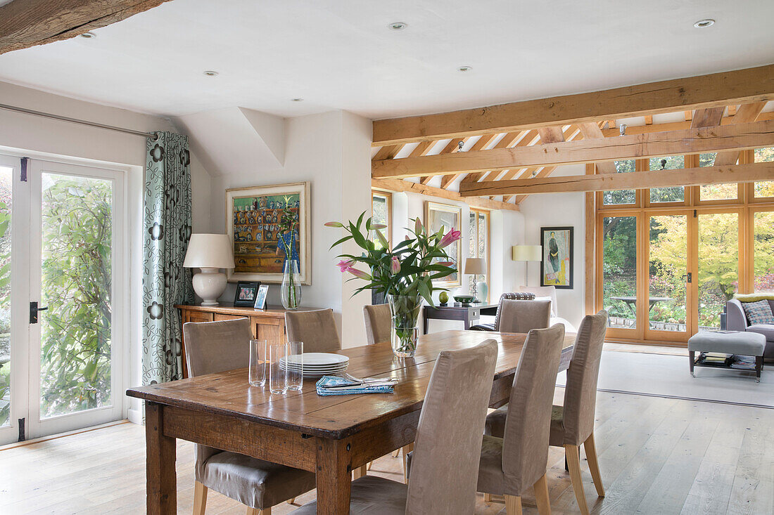 Lilies and plates on table in open plan extension of timber framed farmhouse in Kent UK