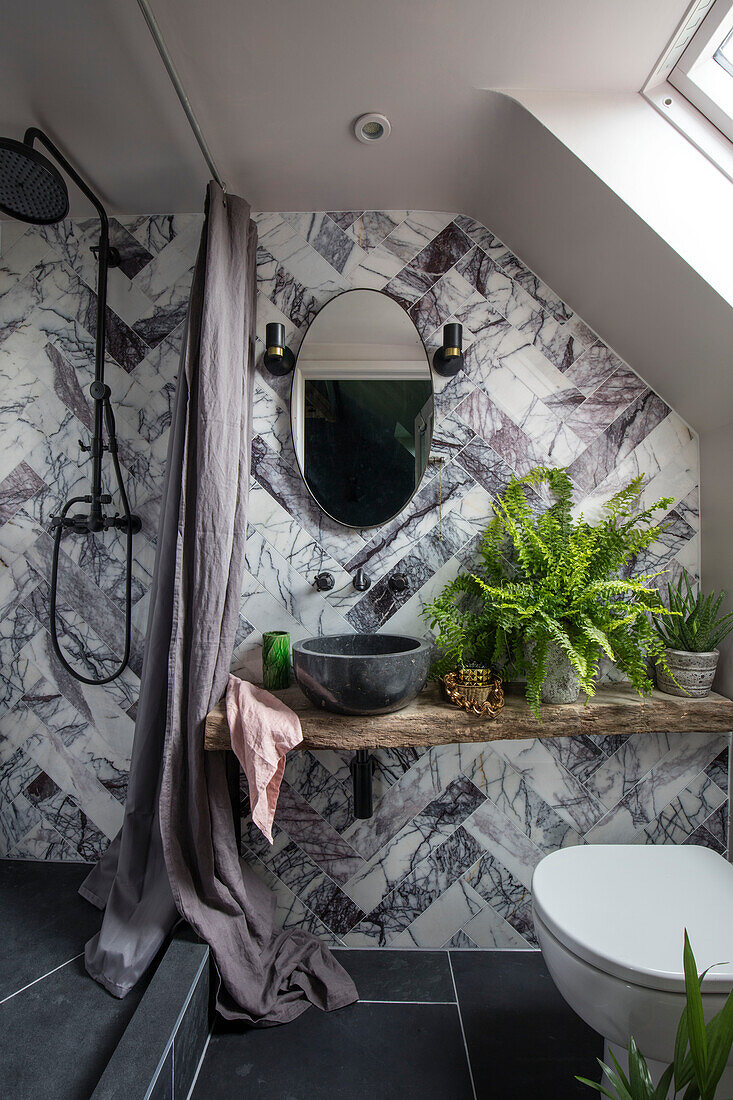 Badezimmer aus poliertem Calacatta-Marmor mit Duschvorhang aus gewaschenem Leinen und Farnen in einer umgebauten walisischen Scheune in Großbritannien