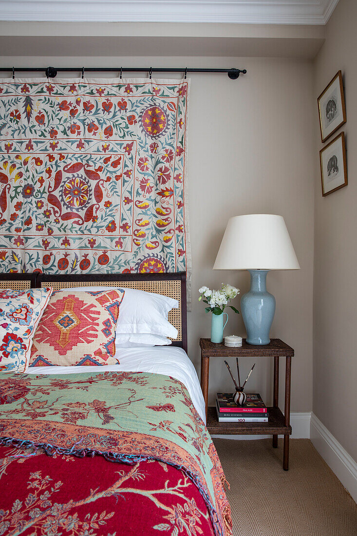 Double bed with decorative handmade textiles in North London apartment UK