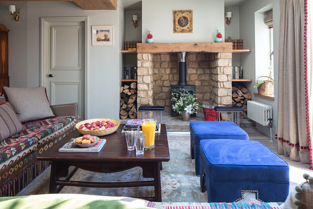 Wood burning stove and blue footstools with walls in 'Gooseberry Fool' 1840s Cotswolds cottage Oxfordshire UK