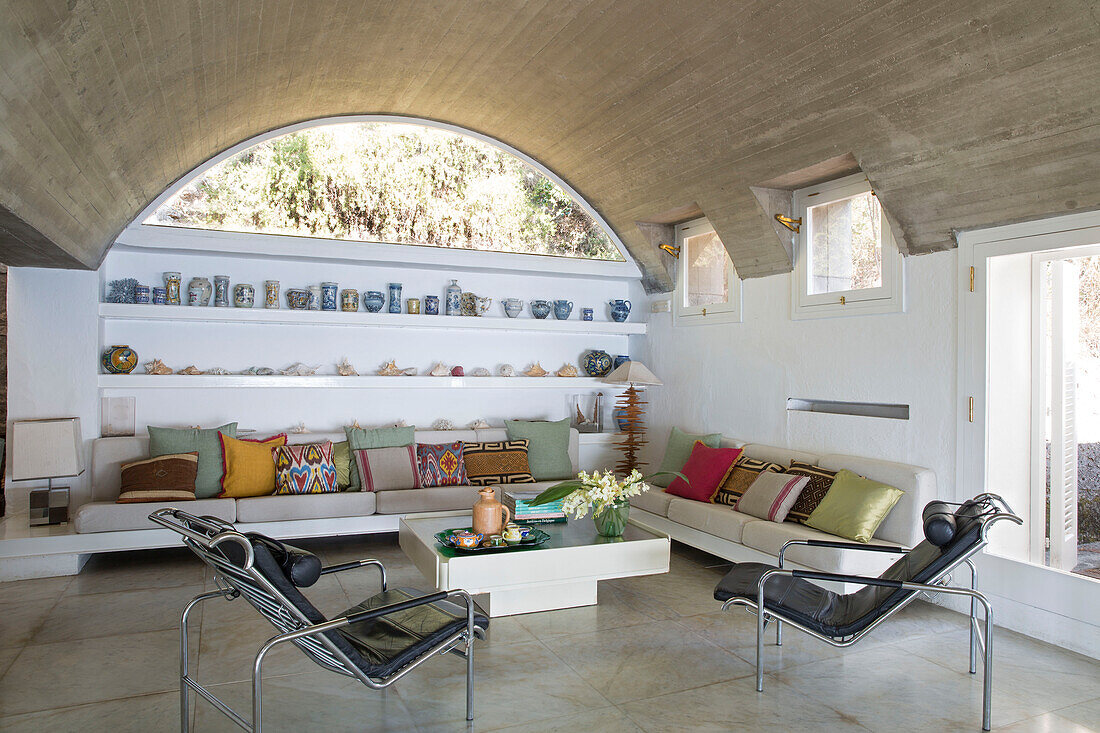 Sofas and cushions with black leather chairs and shelving in Italian villa on the Amalfi coast